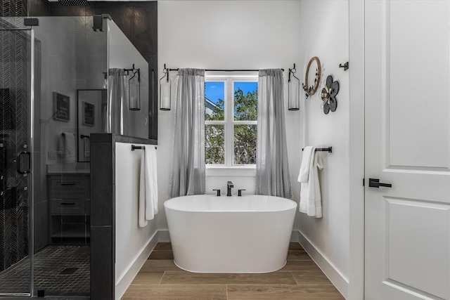 224 Kellog, Fischer, TX 78623 - bathroom featuring a stall shower, a soaking tub, wood finished floors, and baseboards