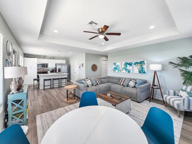 1062 Cedar Ln, Gilchrist, TX 77617 - living room with a tray ceiling, ceiling fan, light wood-style floors, baseboards, and recessed lighting