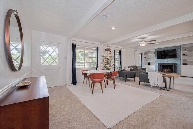 13018 Vernon Rd, Cypress, TX 77429 - dining room with light colored carpet, beam ceiling, a textured ceiling, a large fireplace, and a ceiling fan