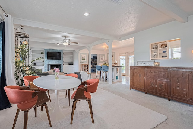 13018 Vernon Rd, Cypress, TX 77429 - dining space featuring beamed ceiling, a ceiling fan, a fireplace, a textured ceiling, and light colored carpet