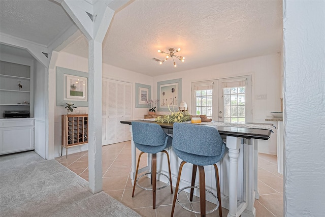 13018 Vernon Rd, Cypress, TX 77429 - kitchen with a textured ceiling, light tile patterned floors, a kitchen bar, and built in shelves