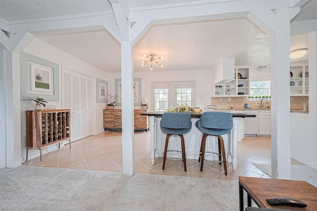 13018 Vernon Rd, Cypress, TX 77429 - kitchen with white cabinets, healthy amount of natural light, a kitchen bar, a sink, and a textured ceiling