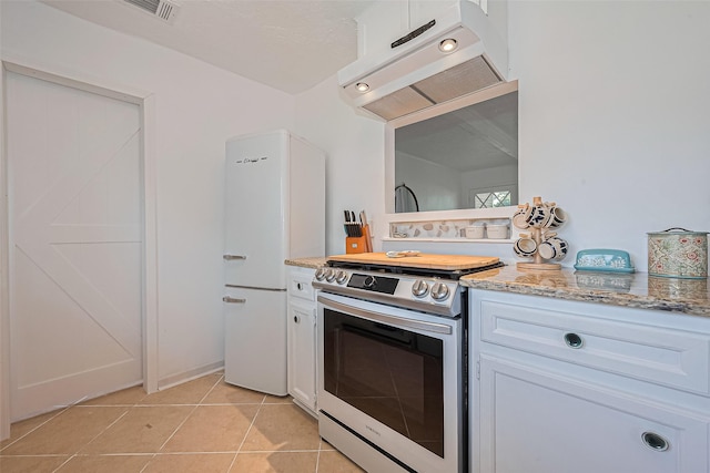 13018 Vernon Rd, Cypress, TX 77429 - kitchen featuring stainless steel gas stove, under cabinet range hood, freestanding refrigerator, light tile patterned floors, and white cabinets