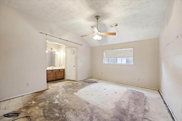 unfurnished bedroom featuring a textured ceiling, vaulted ceiling, ensuite bath, and ceiling fan