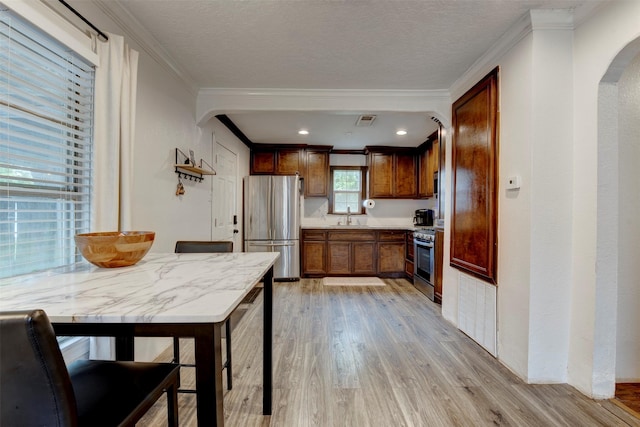 708 Gresham St, Baytown, TX 77520 - kitchen with ornamental molding, a sink, arched walkways, light wood finished floors, and stainless steel appliances
