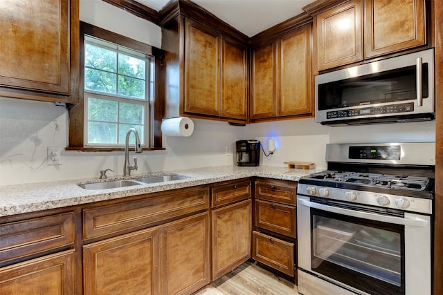 708 Gresham St, Baytown, TX 77520 - kitchen featuring a sink, light stone counters, stainless steel appliances, and light wood-type flooring