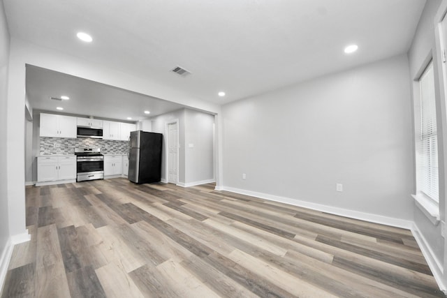 unfurnished living room with recessed lighting, baseboards, visible vents, and light wood-style floors