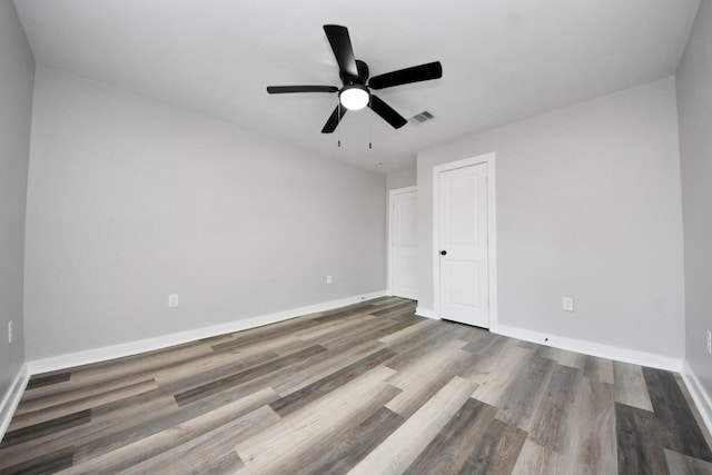 unfurnished room with baseboards, a ceiling fan, wood finished floors, and visible vents