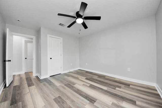 unfurnished bedroom with baseboards, a ceiling fan, wood finished floors, and visible vents