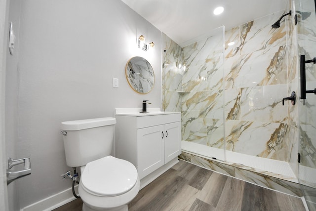 bathroom with vanity, a marble finish shower, wood finished floors, and toilet