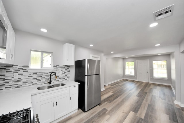 kitchen featuring decorative backsplash, visible vents, a sink, white cabinets, and freestanding refrigerator