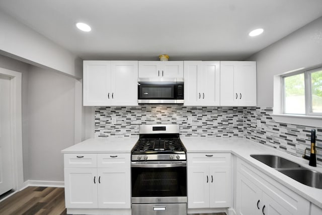 kitchen featuring backsplash, a sink, light countertops, white cabinets, and stainless steel appliances