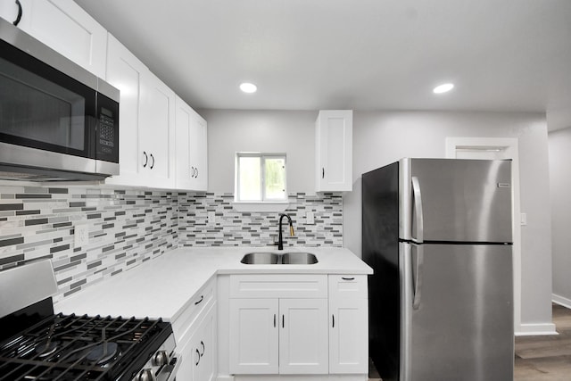 kitchen with white cabinets, a sink, light countertops, stainless steel appliances, and decorative backsplash
