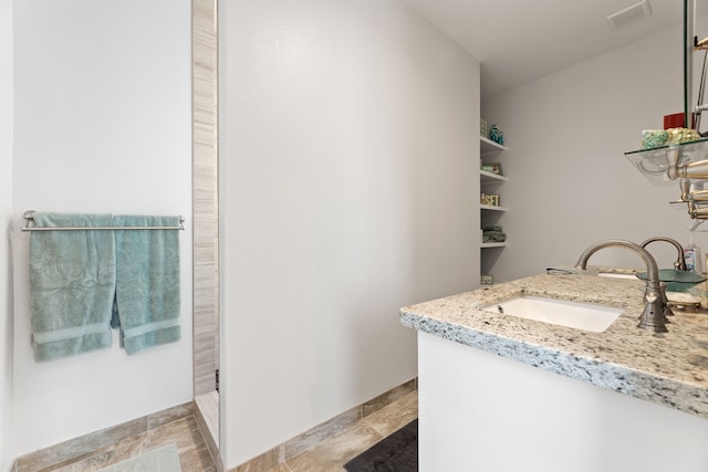 full bathroom with vanity, baseboards, walk in shower, and visible vents
