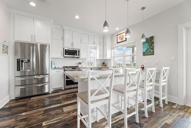 kitchen featuring appliances with stainless steel finishes, a breakfast bar area, recessed lighting, white cabinetry, and dark wood-style floors