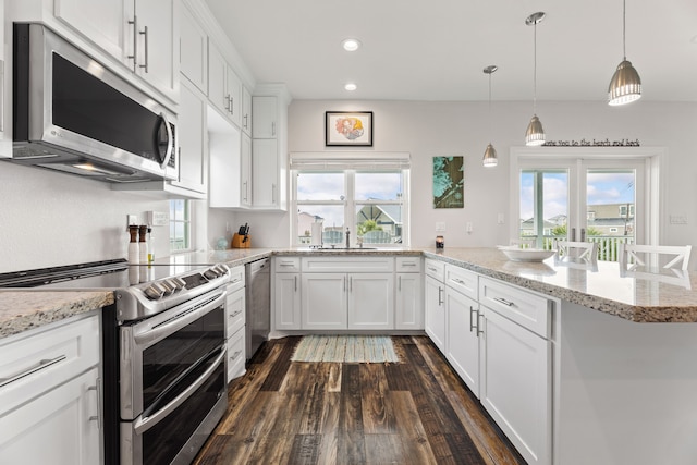kitchen with dark wood-type flooring, recessed lighting, white cabinets, a sink, and stainless steel appliances