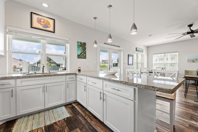 kitchen with dark wood-style flooring, a ceiling fan, hanging light fixtures, and white cabinetry