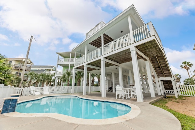 back of house featuring fence, a fenced in pool, a patio area, and a balcony