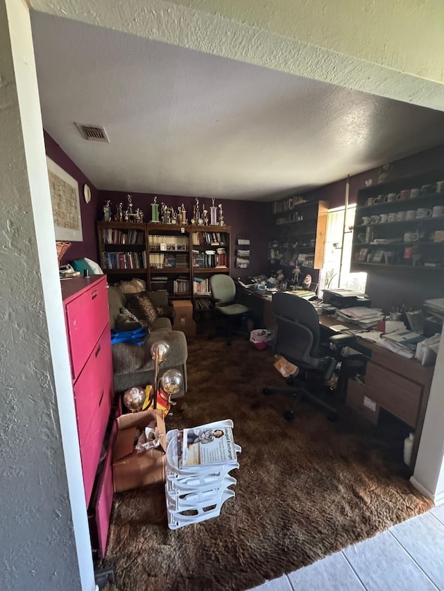 tiled office space with visible vents, carpet flooring, and a textured ceiling