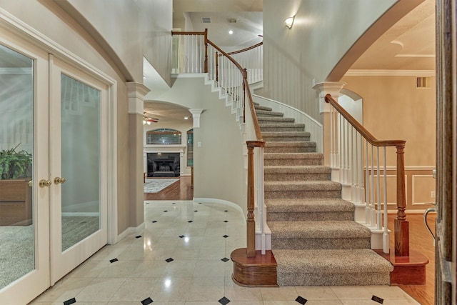 stairway featuring decorative columns, tile patterned floors, a towering ceiling, arched walkways, and ornamental molding