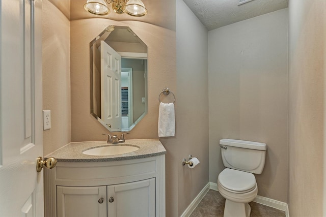 half bath with toilet, vanity, tile patterned floors, and baseboards