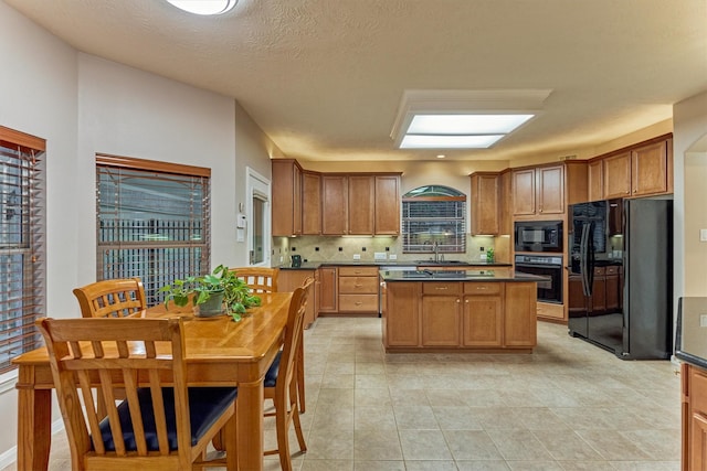kitchen with black appliances, a sink, decorative backsplash, and dark countertops