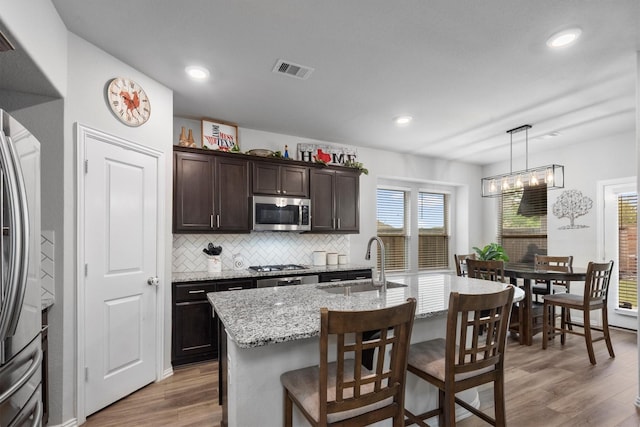 15502 Bosque Valley Ct, Cypress, TX 77433 - kitchen with dark brown cabinetry, appliances with stainless steel finishes, a breakfast bar, a sink, and visible vents