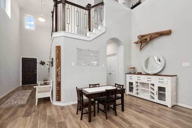 15502 Bosque Valley Ct, Cypress, TX 77433 - dining space featuring arched walkways, a high ceiling, baseboards, and wood finished floors