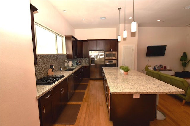 3804 Lovejoy St, Houston, TX 77003 - kitchen featuring decorative backsplash, a kitchen island, appliances with stainless steel finishes, a sink, and open floor plan