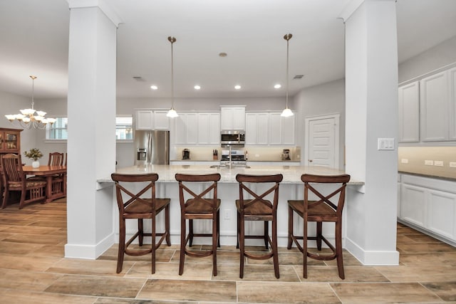 kitchen with stainless steel appliances, light wood-style flooring, a chandelier, a kitchen bar, and recessed lighting