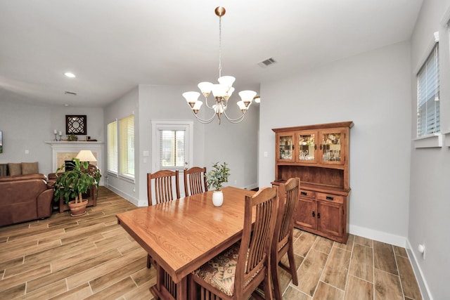 dining space with wood tiled floors, baseboards, a chandelier, and recessed lighting