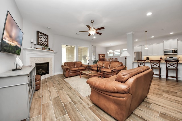 living area featuring ceiling fan, recessed lighting, wood tiled floors, a tile fireplace, and baseboards