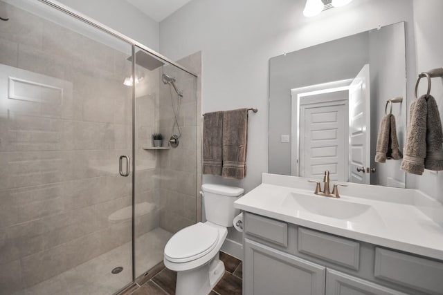 bathroom with toilet, a stall shower, and vanity