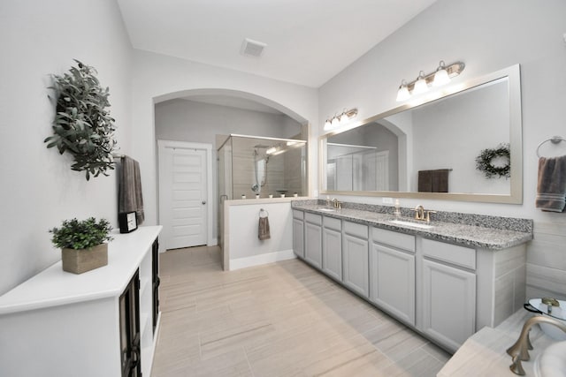 full bathroom with a shower stall and double vanity