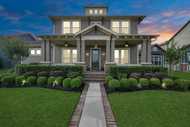american foursquare style home featuring ceiling fan, covered porch, and a front yard