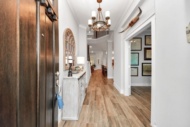 entryway with a chandelier, light wood finished floors, and baseboards