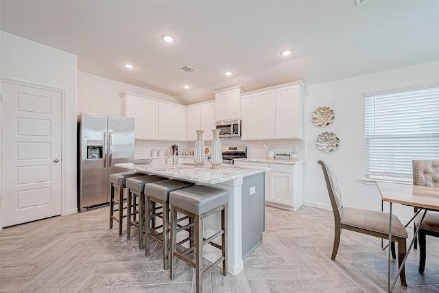 26234 Cooperstown Way, Splendora, TX 77372 - kitchen featuring white cabinets, a kitchen bar, and stainless steel appliances