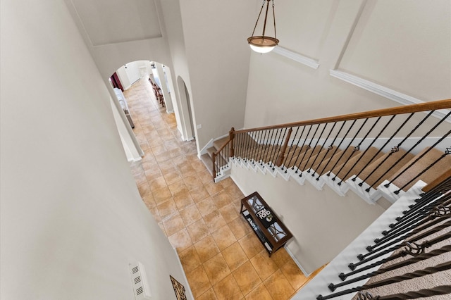 staircase with arched walkways and tile patterned floors