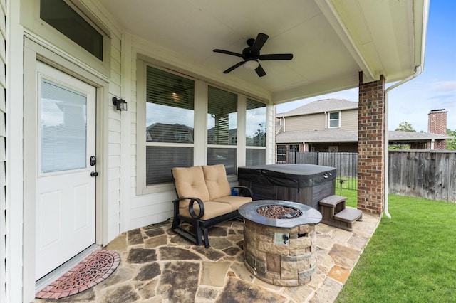 view of patio with a fenced backyard, ceiling fan, a hot tub, and an outdoor fire pit