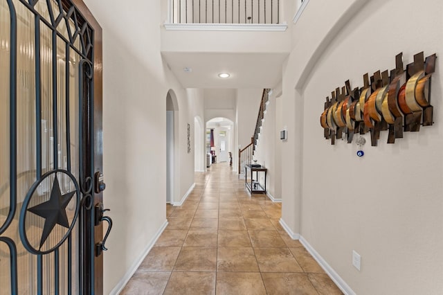entryway with arched walkways, a high ceiling, and baseboards