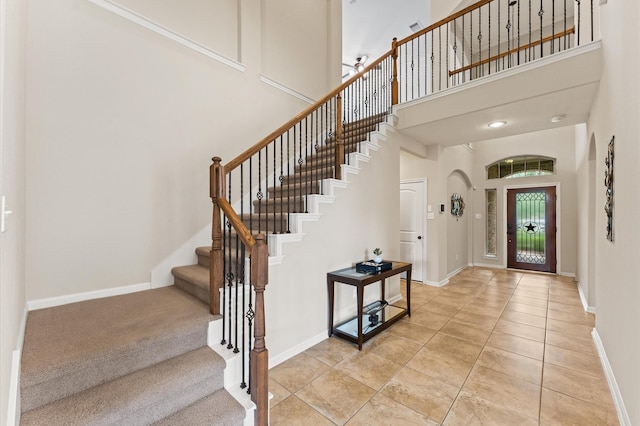 foyer with a high ceiling, baseboards, and stairway