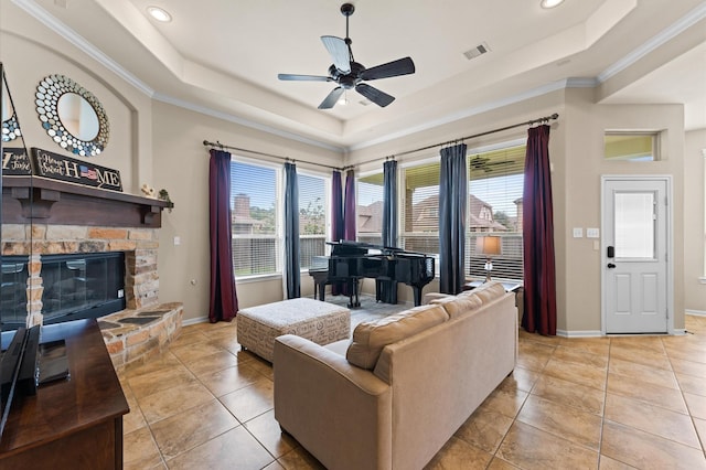 living room featuring a ceiling fan, visible vents, a raised ceiling, baseboards, and ornamental molding