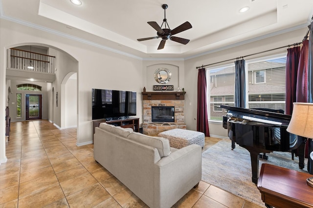 living room featuring light tile patterned floors, arched walkways, plenty of natural light, and a tray ceiling