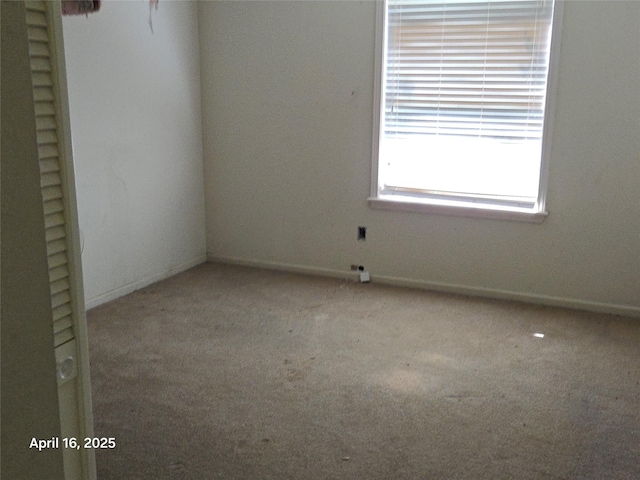 spare room with baseboards and light colored carpet