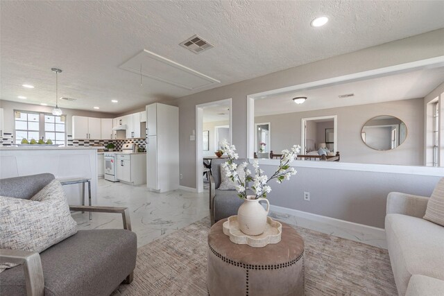 12928 John Reynolds Rd, Galveston, TX 77554 - living area featuring attic access, a textured ceiling, visible vents, baseboards, and marble finish floor