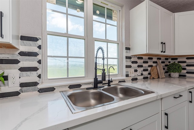 12928 John Reynolds Rd, Galveston, TX 77554 - kitchen with white cabinetry, decorative backsplash, and a sink