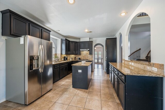 3011 Rustic Gardens Dr, Spring, TX 77386 - kitchen featuring appliances with stainless steel finishes, arched walkways, a sink, light stone countertops, and tasteful backsplash