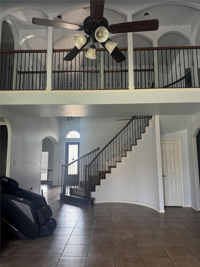 3011 Rustic Gardens Dr, Spring, TX 77386 - staircase with a towering ceiling, ceiling fan, tile patterned flooring, arched walkways, and baseboards