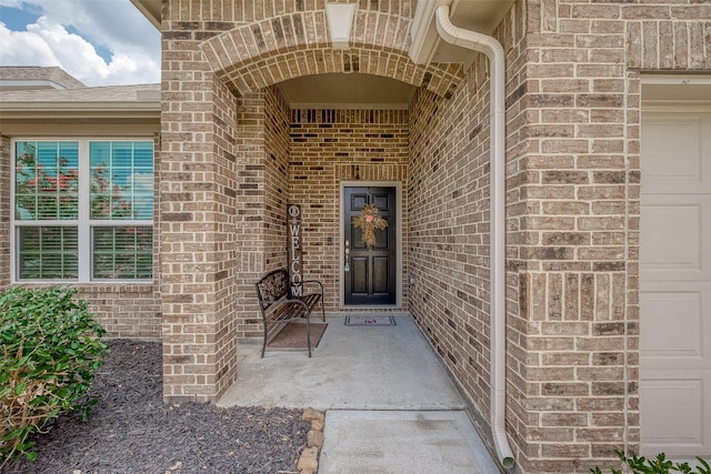 view of exterior entry featuring brick siding