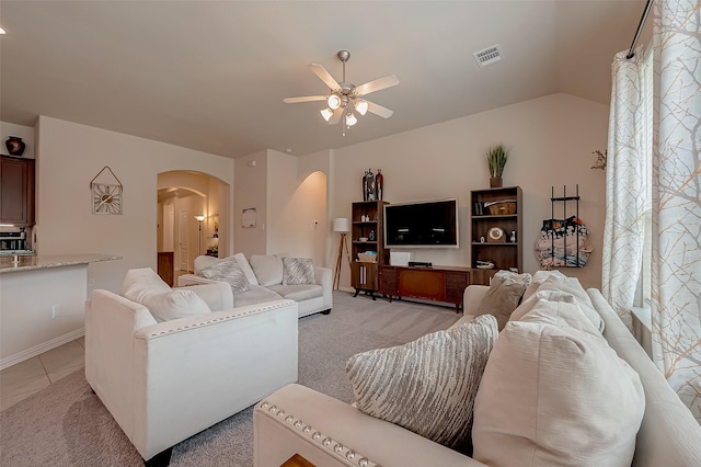 living area featuring visible vents, arched walkways, baseboards, and ceiling fan